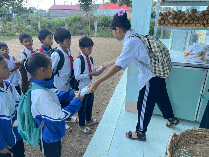 Học sinh của thầy Vũ Văn Tùng tham gia phân phát bánh mì cho các em nhỏ. Ảnh: NVCC z5884333300497_dd766ff492fb185536522bfec1451665.jpg