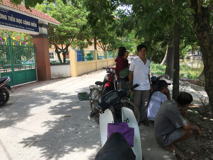 Từ sáng sớm đến trưa ngày 9/7 nhiều phụ huynh có con, cháu học Trường Tiểu học Cộng Hiền đến cổng trường chờ phóng viên để phản ánh bức xúc nhiều năm qua. Ảnh: Vũ Phương.