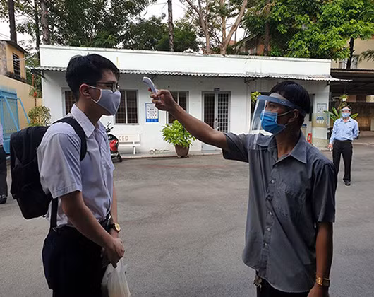 Học sinh được đo thân nhiệt khi đến trường để phòng chống Covid-19 (ảnh: P.L)