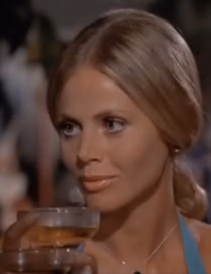 5. Goodnight (do Britt Ekland đóng), tập phim The Man With The Golden Gun (1974) - Xẻ tóc ngôi giữa rồi chải toàn bộ tóc ra sau, buộc kiểu đuôi ngựa thấp - Đánh rối phần đuôi tóc rồi cuộn tròn thành búi nhỏ - Thoa tinh dầu dưỡng lên phần tóc phía trước để hoàn thành các bước thực hiện.