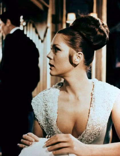 3. Tracy Di Vincenzo (do Diana Rigg đóng), tập phim On Her Majesty’s Secret Service (1969) Kiểu tóc búi to sang trọng này rất dễ thực hiện: - Buộc gập đuôi tóc lên cao giống như tóc đuôi ngựa - Kéo nhẹ đuôi tóc ra xung quanh, tạo thành một búi hình tròn rồi dùng cặp ghim cố định hình dáng. - Cuối cùng, xịt keo giữ nếp