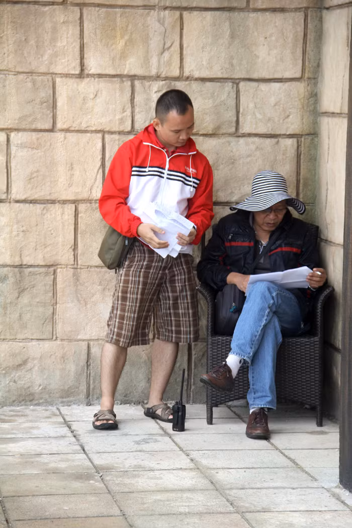 MC Lại Văn Sâm đội mũ rộng vành, ngồi kín đáo trong một góc tường bàn công việc.