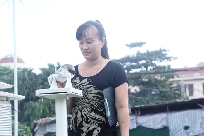 Chị Vũ Thị May, cán bộ trại trạm khí tượng Láng đang xem thông số trên máy Nhật quang ký dùng để đo thời gian nắng trong ngày (ảnh Viết Cường)