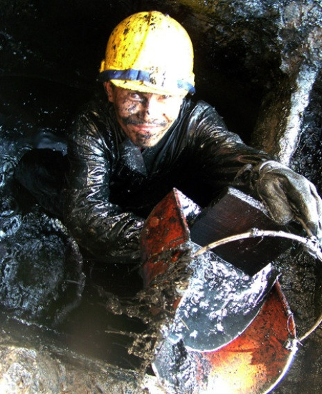 Suốt ngày tiếp xúc với bùn dơ, nhưng lương của người công nhân móc cống quá thấp so với giám đốc - Ảnh: T.TRUNG (Tuổi Trẻ)