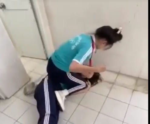 Nữ sinh Trường Võ Văn Kiệt, Kiên Giang đè bạn ra sàn nhà vệ sinh, đánh bạn (ảnh cắt từ video clip) nusinhVVKRGia.jpg