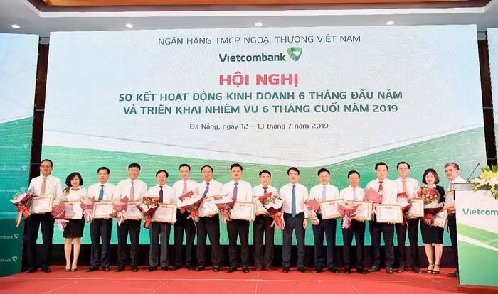 Chủ tịch Hội đồng Quản trị Nghiêm Xuân Thành (thứ 7 từ phải sang) và Tổng giám đốc Phạm Quang Dũng (thứ 6 từ trái sang) trao Giấy khen và tặng hoa cho 14 chi nhánh tiêu biểu trên một số mặt hoạt động 6 tháng đầu năm 2019
