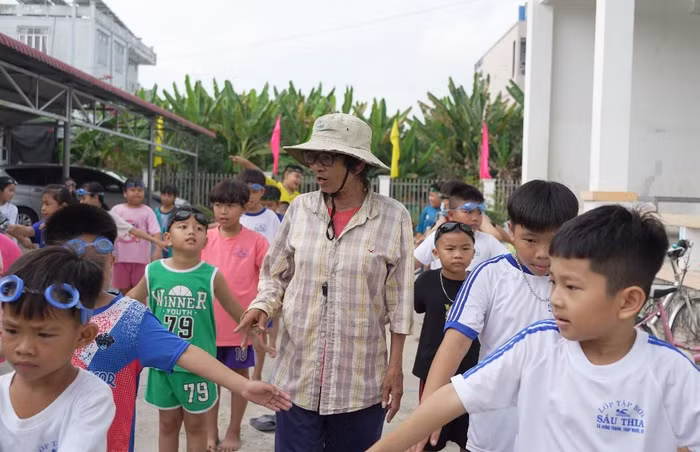 Bà Sáu Thia hướng dẫn các em nhỏ khởi động trước khi vào hồ học bơi.