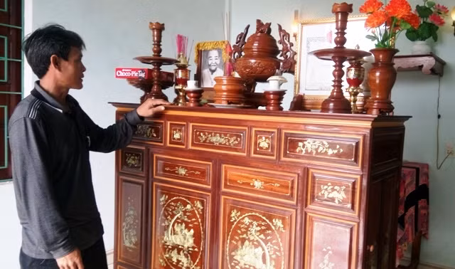 Anh Lợi bên bàn thờ của ông bà nuôi. (Ảnh: Thủy Phan)