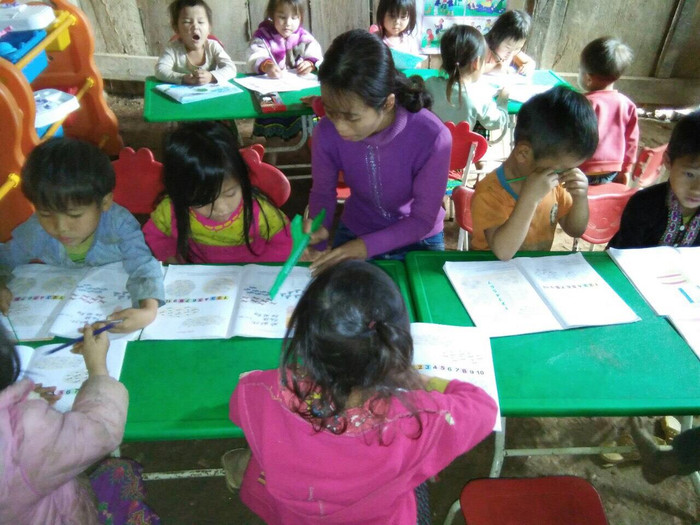 Học sinh được cô giáo hướng dẫn đọc và viết, nhiều trẻ đến lớp chưa nói được tiếng phổ thông, các em vẫn giao tiếp với cô bằng tiếng dân tộc. Ảnh: GVCC.