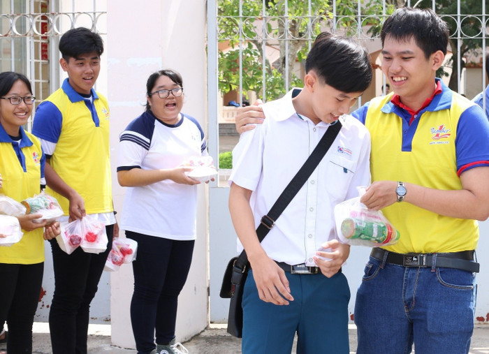 Các tình nguyện viên trao phần cơm trưa cho các thí sinh bên ngoài cổng trường Các tình nguyện viên trao phần cơm trưa cho các thí sinh bên ngoài cổng trường