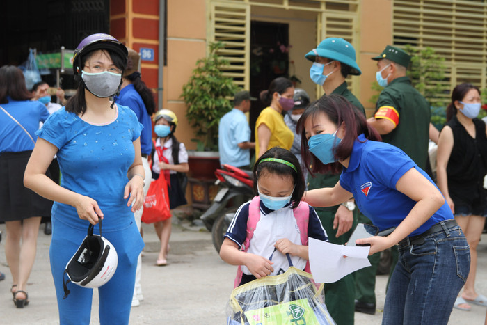 Từ sớm phụ huynh Trường Tiểu học Long Biên đưa con đến cổng trường được thầy cô giáo đón. Ảnh: Vũ Phương
