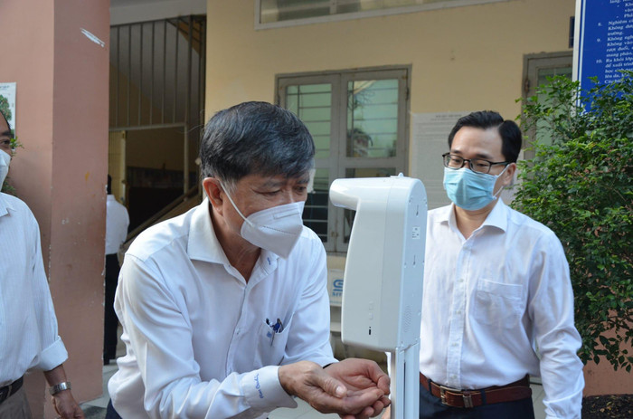 Giám đốc Sở Giáo dục Thành phố Hồ Chí Minh rửa tay sát khuẩn trước khi vào trường Lý Phong (ảnh: CTV)