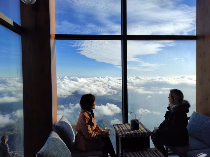 Ngoài sàn cột cờ, đường La Hán, du khách còn có thể lựa chọn cà phê Du Soleil để “săn” mùa mây Fansipan. Còn gì hơn khi vừa được nhâm nhi tách trà táo quế, cacao ấm nóng cùng những vị bánh kem ngọt ngào, vừa được ngắm biển mây bồng bềnh giữa núi rừng hùng vĩ. Ảnh: Tư liệu 2022 Ngoài sàn cột cờ, đường La Hán, du khách còn có thể lựa chọn cà phê Du Soleil để “săn” mùa mây Fansipan. Còn gì hơn khi vừa được nhâm nhi tách trà táo quế, cacao ấm nóng cùng những vị bánh kem ngọt ngào, vừa được ngắm biển mây bồng bềnh giữa núi rừng hùng vĩ. Ảnh: Tư liệu 2022