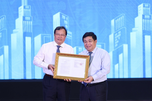 Bộ trưởng Bộ Kế hoạch và Đầu tư Nguyễn Chí Dũng trao Quy hoạch tỉnh Trà Vinh thời kỳ 2021-2030, tầm nhìn đến năm 2050 cho Chủ tịch Uỷ ban nhân dân tỉnh Trà Vinh Lê Văn Hẳn. Ảnh: VGP/Nhật Bắc