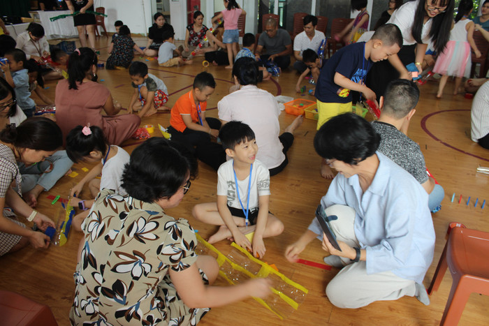 Sau phần đọc cuốn truyện Cầu trượt thật dài, phụ huynh và học sinh cùng làm cầu trượt bằng những chai nhựa đã sử dụng. Ảnh: Vũ Phương.