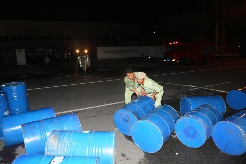 Công nhân đang cố gắng mang ra những thùng hóa chất bên trong hiện trường nhằm hạn chế nổ dữ dội (Ảnh: Thiên Lý)