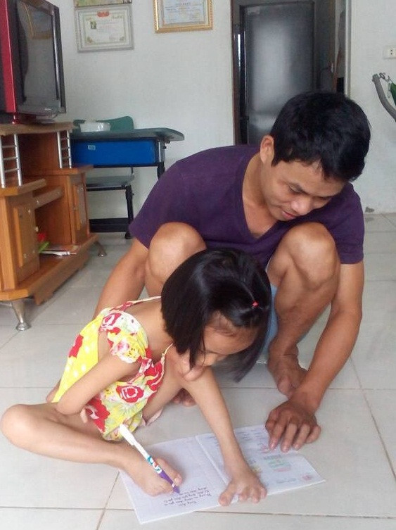 Bé Linh đang làm bài tập với sự hướng dẫn của bố.