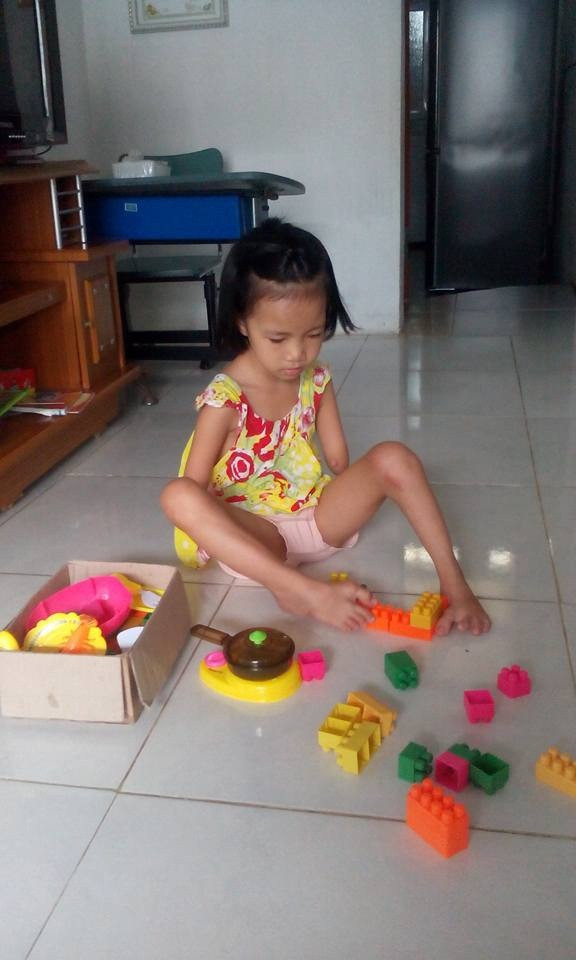 Linh khéo léo xếp đồ chơi bằng đôi chân.