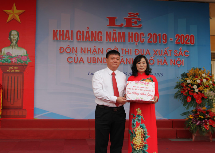 Cô Đồng Thị Quyên nhận quà từ đại diện Ủy ban nhân dân phường Long Biên dành tặng cho những học sinh có khoàn cảnh khó khăn. Ảnh: Vũ Phương.