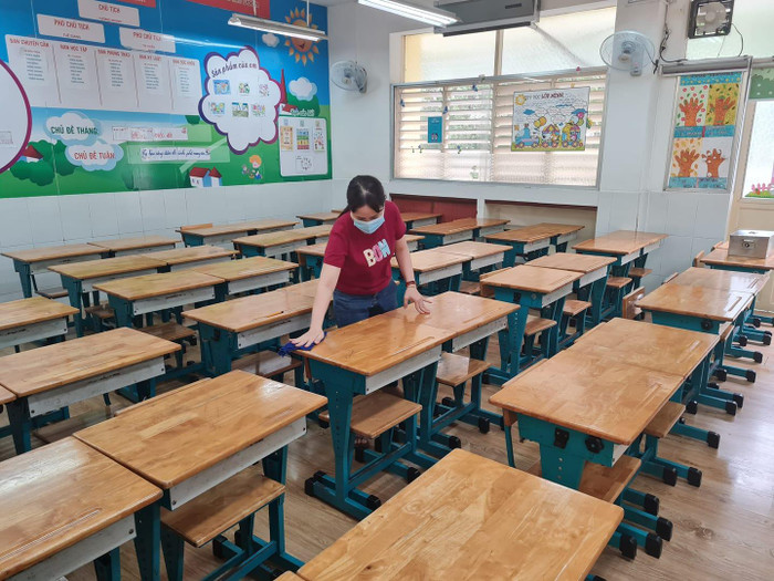 Nhân viên trường tiểu học Nguyễn Bỉnh Khiêm vệ sinh bàn ghế đón học sinh quay lại học (ảnh: P.L)