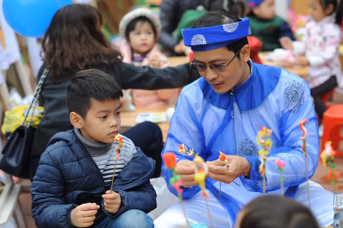 Các em học sinh chăm chú khi được nghệ nhân giải thích ý nghĩa của những hình tò he truyền thống.