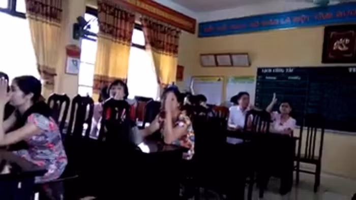 Hình ảnh cán bộ, giáo viên nhà trường dưới sự chỉ đạo của hiệu trưởng đã giơ tay hạ mức hoàn thành nhiệm vụ cô Nhung xuống mức không hoàn thành nhiệm vụ. Ảnh: Cắt từ video NVCC.