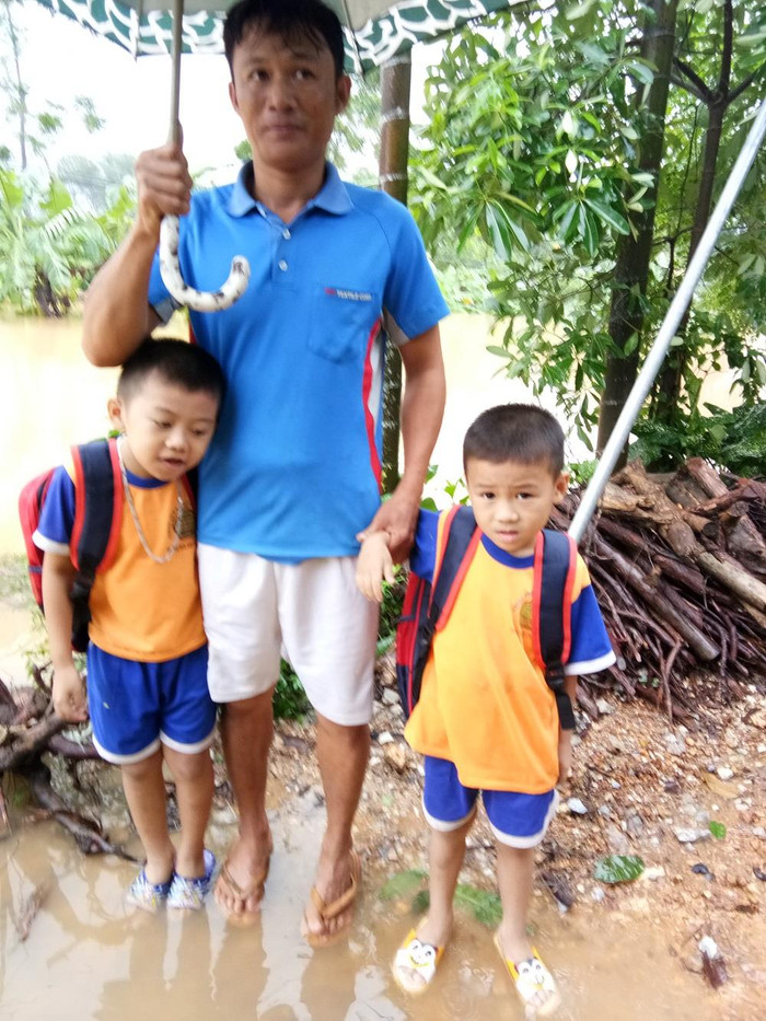 Ông Lê Đình Cường đưa 2 con ra ngõ, nước ngập mênh mông, dỗ mãi 2 con mới chịu vào nhà