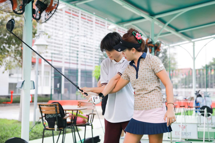 Huấn luyện viên trưởng bộ môn golf của EQuest NGô Bảo Nghi đang hướng dẫn học sinh kĩ thuật golf Huấn luyện viên trưởng bộ môn golf của EQuest NGô Bảo Nghi đang hướng dẫn học sinh kĩ thuật golf
