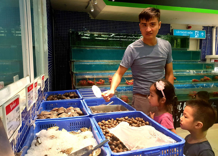 Hai cháu bé đang chăm chú khi được bố dạy cho cách phân biệt các loại ốc, ngao tại khu vực quầy tươi sống của VinMart. Hai cháu bé đang chăm chú khi được bố dạy cho cách phân biệt các loại ốc, ngao tại khu vực quầy tươi sống của VinMart.