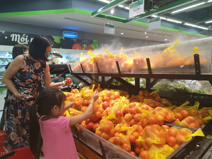Một bé gái đang học cách chọn cà chua cùng mẹ tại VinMart Times City Một bé gái đang học cách chọn cà chua cùng mẹ tại VinMart Times City