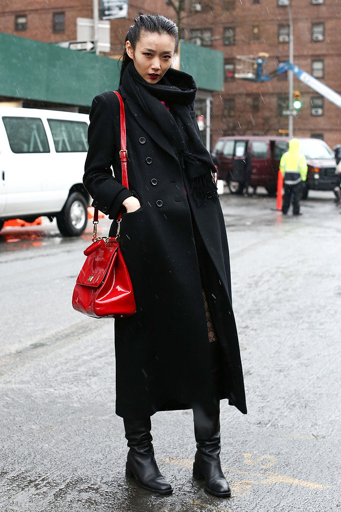 Huyền bí nhưng không kém phần sang trọng - đó là cách kết hợp giữa áo khoác oversized dáng dài quá đầu gối màu đen, bốt da cao cổ ton-sur-ton và chiếc túi da bóng màu đỏ, một điểm nhấn ngọt ngào cho tổng thể trang phục.