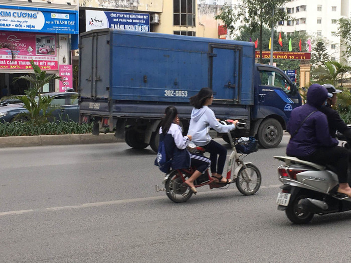 Hai học sinh đi xe máy điện không đội mũ bảo hiểm trên đường Quang Trung, quận Hà Đông. Hai học sinh đi xe máy điện không đội mũ bảo hiểm trên đường Quang Trung, quận Hà Đông.