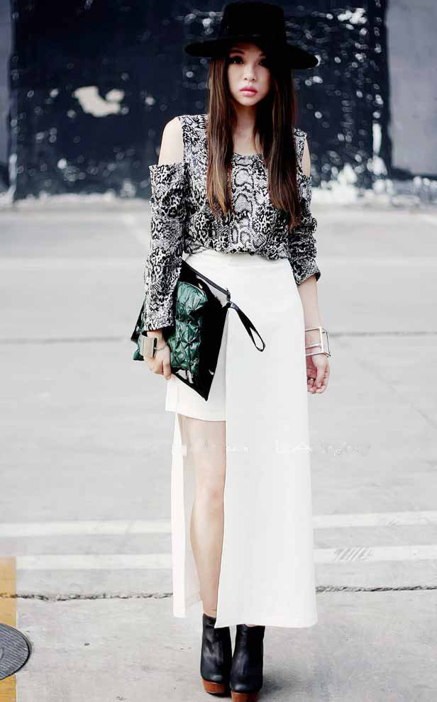 Một chiếc váy dài màu trắng với những đường xẻ phá cách làm nổi bật chiếc áo họa tiết da rắn sang trọng và quyến rũ.