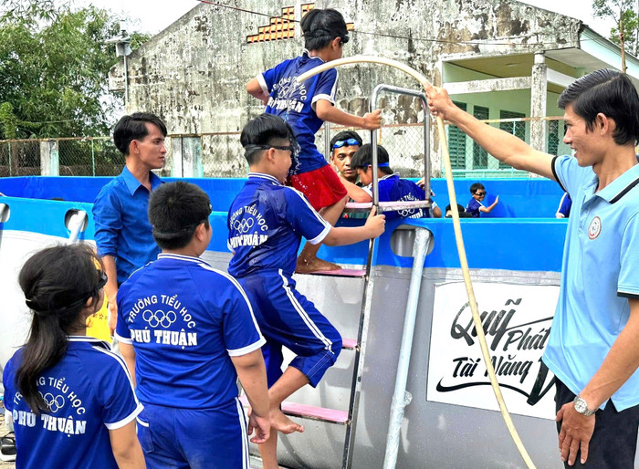 Học sinh được các thầy rửa chân sạch trước khi vào học bơi trong hồ mới.jpg