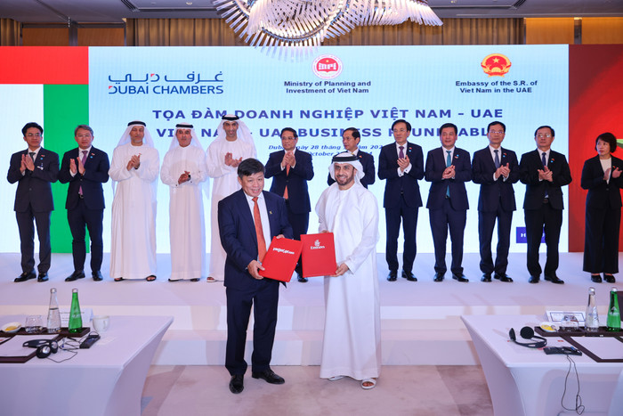 Đại diện lãnh đạo Vietjet (trái) và Emirates (phải) trao thỏa thuận hợp tác mở rộng kết nối quốc tế trước sự chứng kiến của Thủ tướng Phạm Minh Chính (giữa) tại Dubai, UAE. Photo 1 (7).jpg
