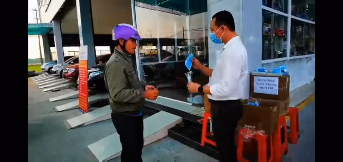 Thầy giáo Nguyễn Kim Tâm (bên phải) phát khẩu trang miễn phí cho người dân