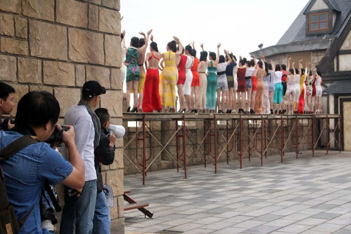 Các thí sinh được ghi hình vẫy tay chào trên một chiếc cầu dựng tạm, bên dưới -phía bên kia bức tường là một khoảng không hun hút. Các thí sinh được ghi hình vẫy tay chào trên một chiếc cầu dựng tạm, bên dưới -phía bên kia bức tường là một khoảng không hun hút.