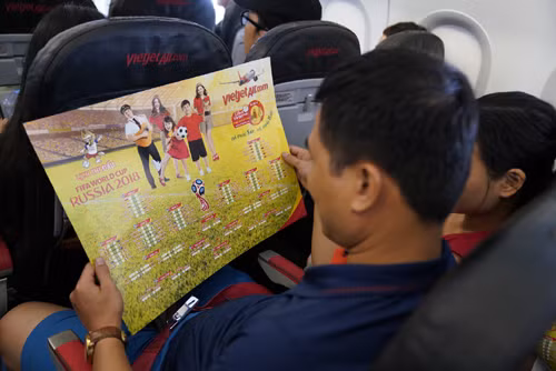 Một hành khách trên tàu bay chăm chú xem lịch thi đấu World Cup 2018 trên bộ lịch thi đấu của Vietjet tặng. Ảnh: Vietjet