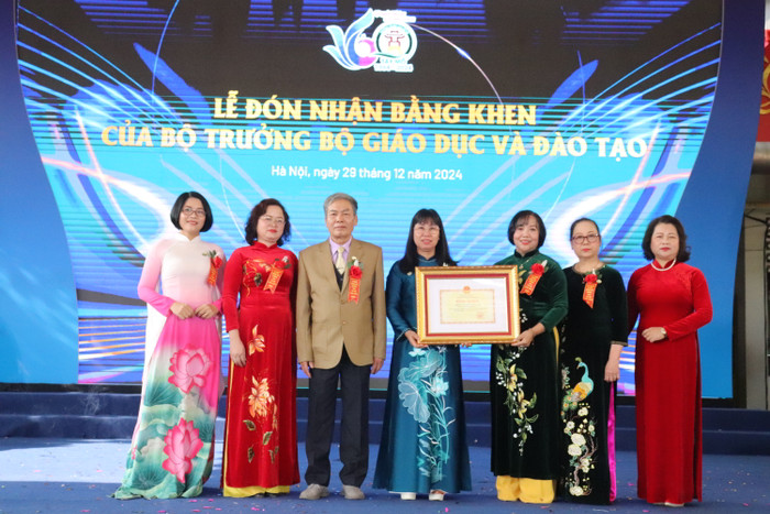 Bà Đỗ Thị Thúy Hà (thứ 4 từ trái sang) - Ủy viên Ban thường vụ quận ủy, Phó Chủ tịch Ủy ban nhân dân quận Nam Từ Liêm đại diện trao bằng khen của Bộ trưởng Bộ Giáo dục và Đào tạo cho lãnh đạo nhà trường. (Ảnh: Nhật Lệ) GDVN-TAY-MO (5).JPG
