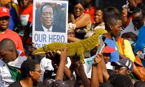 Người dân Zimbabwe mang theo những tấm hình của vị tân Tổng thống để thể hiện sự ủng hộ đối với ông (Ảnh: CNN)