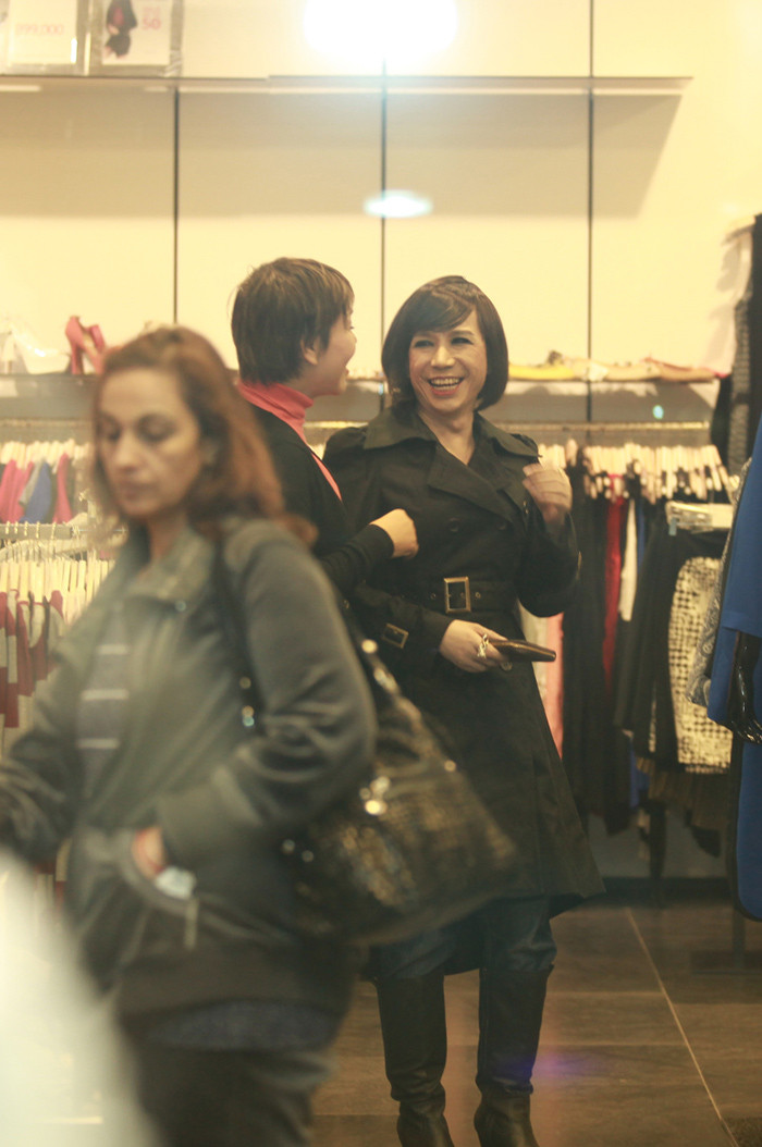 Long Nhật đội tóc giả và trang điểm khá đậm, anh đi bốt, mặc áo măng tô đen dài trông thanh thoát và đầy nữ tính