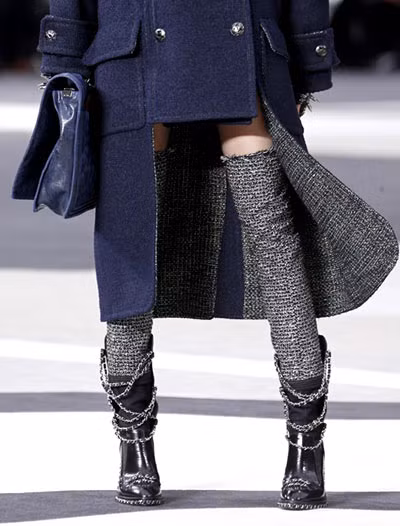 Đôi bốt da với phần cổ "siêu" cao bằng vải tweed và gắn dây xích cá tính trở thành tâm điểm của sàn diễn mùa thu đông năm nay. Kết hợp với áo choàng cắt vạt ngắn phía trước, tác phẩm của thiên tài thiết kế Karl Lagerfeld thể hiện được toàn bộ sự lôi cuốn mạnh mẽ của mình.