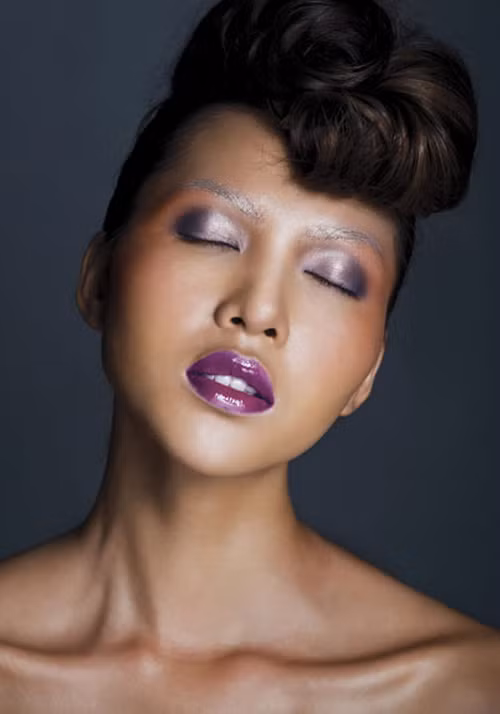 Cô dùng phấn tạo khối nâu đồng, phấn mắt tím nhạt. Gương mặt góc cạnh càng trở nên cá tính với màu son lạ.