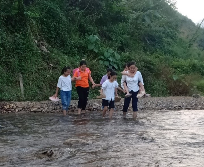Cô Đặng Thị Hương (ngoài cùng bên phải) giúp học sinh vượt suối tới trường. Ảnh: NVCC 5cea5142b5f115af4ce0.jpg