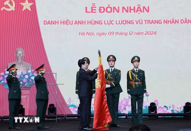 Chủ tịch nước Lương Cường gắn huy hiệu Anh hùng Lực lượng vũ trang nhân dân lên lá cờ truyền thống Viện Hàng không Vũ trụ Viettel. (Ảnh: Lâm Khánh/TTXVN)