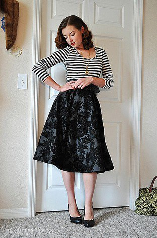 Chân váy nhung trở nên phù hợp với độ tuổi người mặc hơn khi kết hợp với chiếc áo họa tiết kẻ ngang.