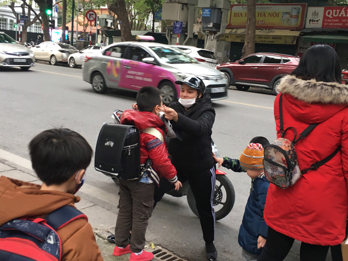 Một phụ huynh Tiểu học Võ Thị Sáu đeo khẩu trang cho con. Ảnh: Vũ Phương.