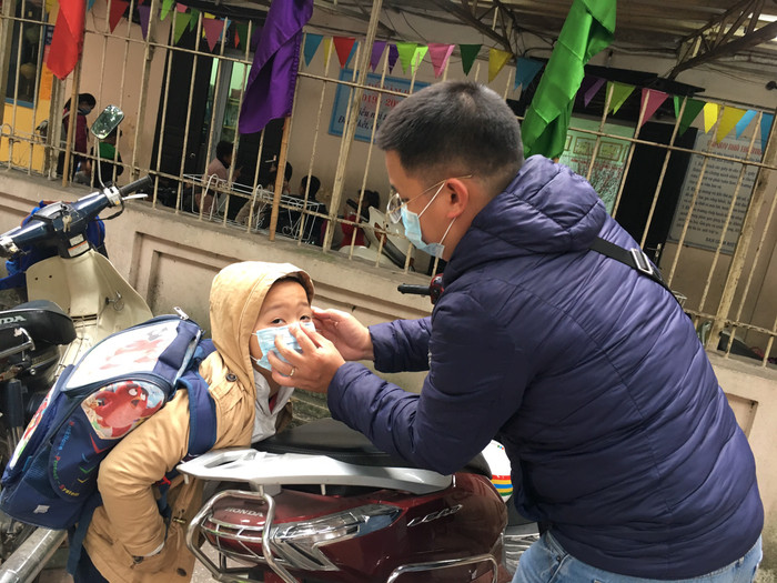 Phụ huynh mua khẩu trang mới đem đến cho con. Ảnh: Vũ Phương.