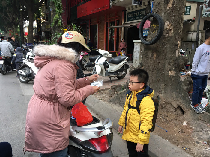 Một phụ huynh Trường tiểu học Võ Thị Sáu (quận Hoàn Kiếm) cẩn thận mang theo khẩu trang mới mua đến đón con để đeo cho con trước khi về nhà. Ảnh: Vũ Phương.
