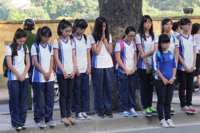 Một tốp học sinh trên đường đi học về, vì đã hết giờ viếng nên đã đứng bên đường nhìn về căn nhà số 30 Hoàng Diệu, chắp tay tỏ lòng thành kính, xót thương sự ra đi củ Đại tướng Võ Nguyên Giáp (Ảnh: Báo Tin Tức)